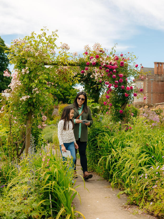 A woman and her child walk through a garden