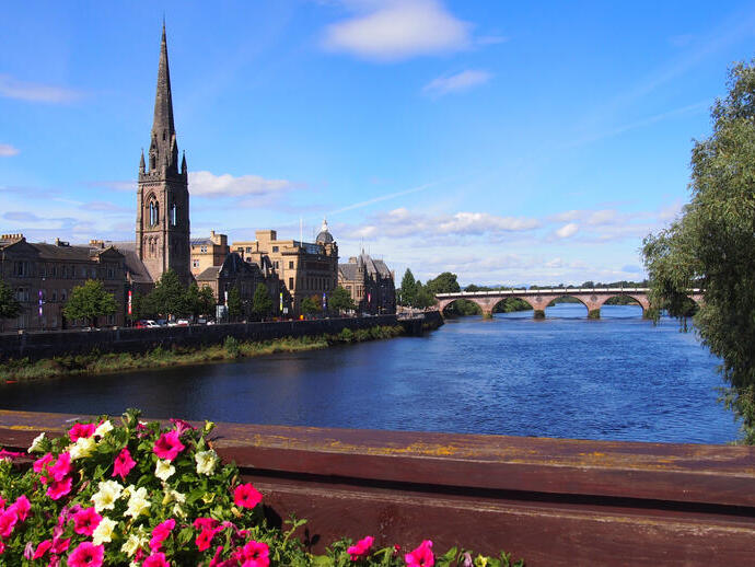 A view across a wide river to a church in the summer