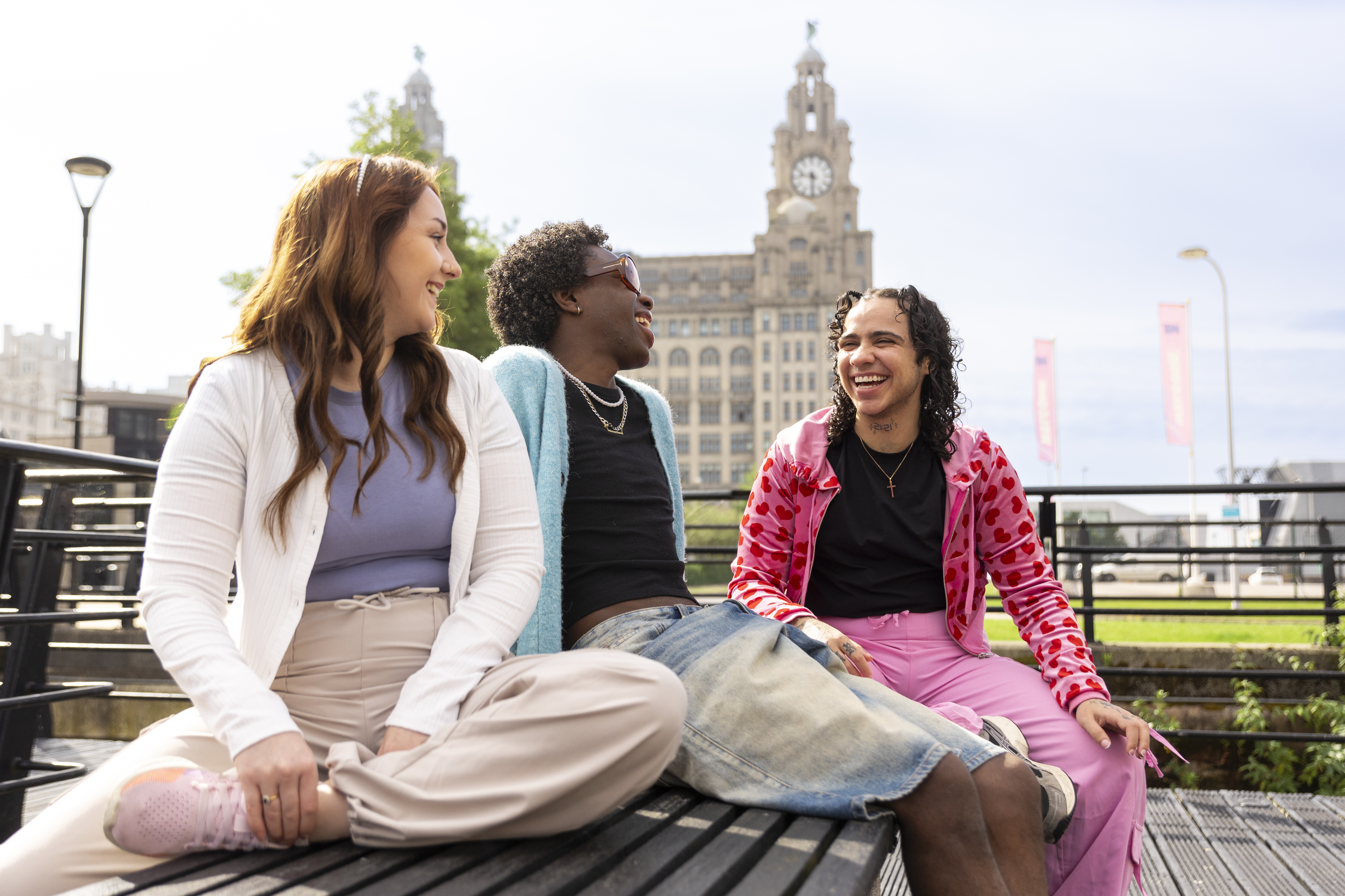 A group of friends sit together on a bench in front of an iconic building