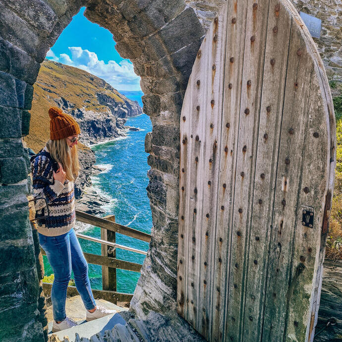 Una mujer de pie en lo alto de las escaleras de una puerta con vistas a la costa al fondo