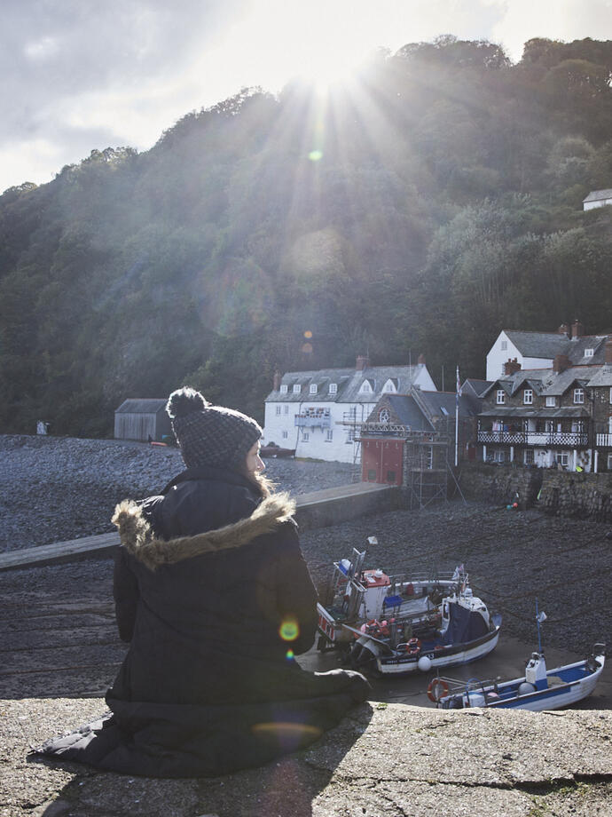 Woman sitting on harbour wall in the sunshine