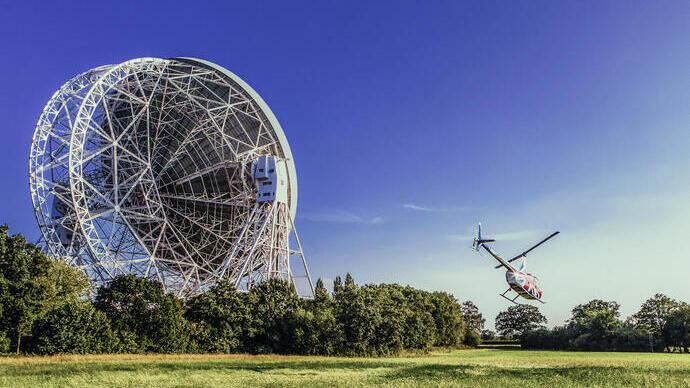 A helicopter flies by a giant telescope