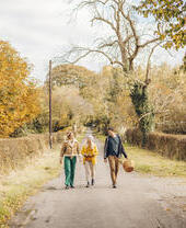 Two women and a man walking on a country lane in autumn