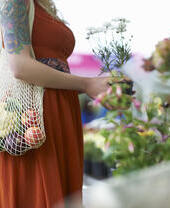 Woman shopping on local market with plastic free reusable bag.
