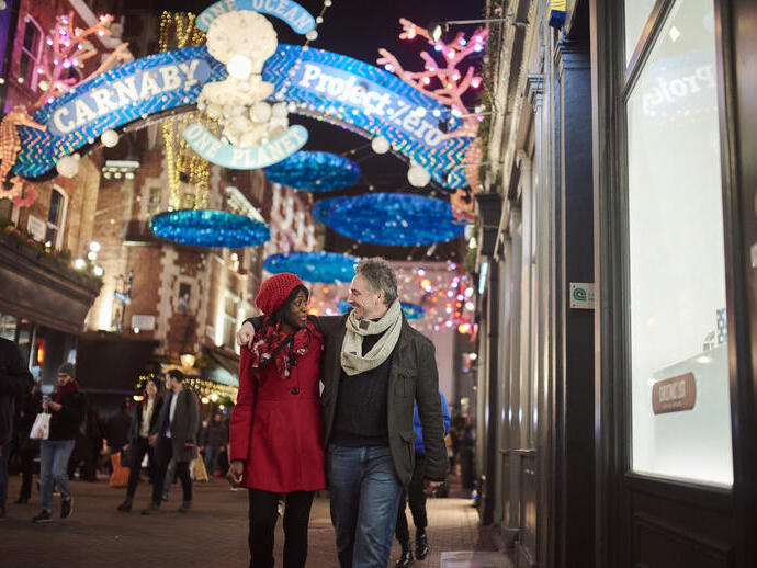 Paar, das unter Weihnachtsbeleuchtung die Straße entlanggeht