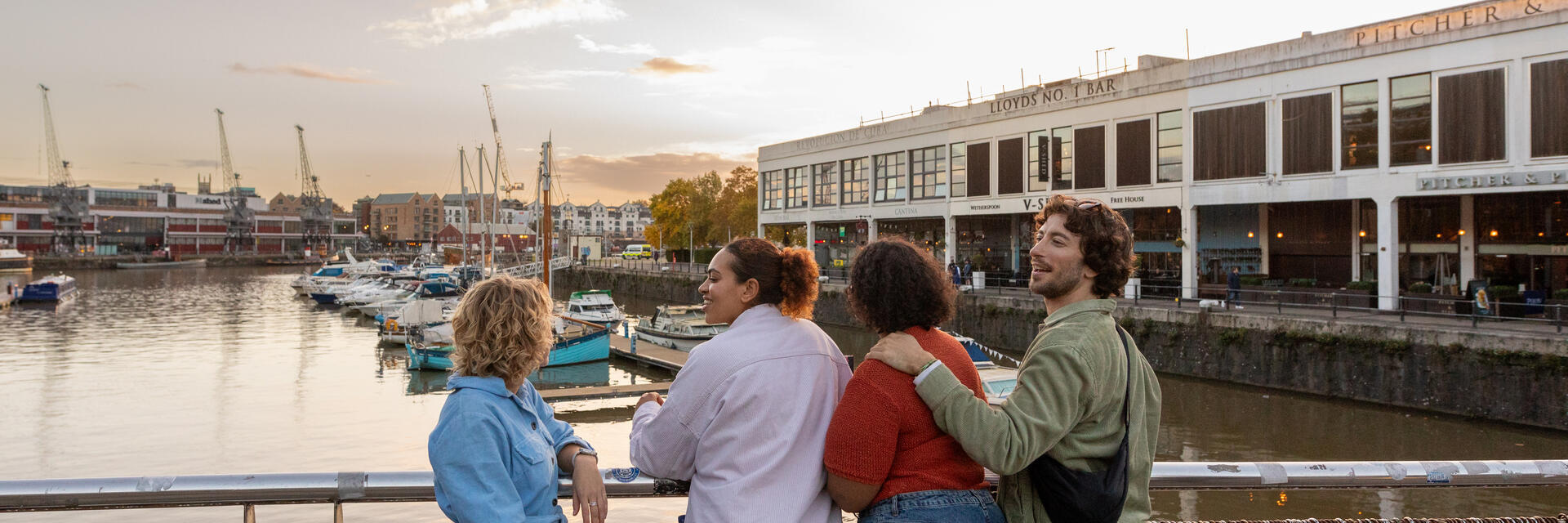 Friends walking over a waterfront bridge.