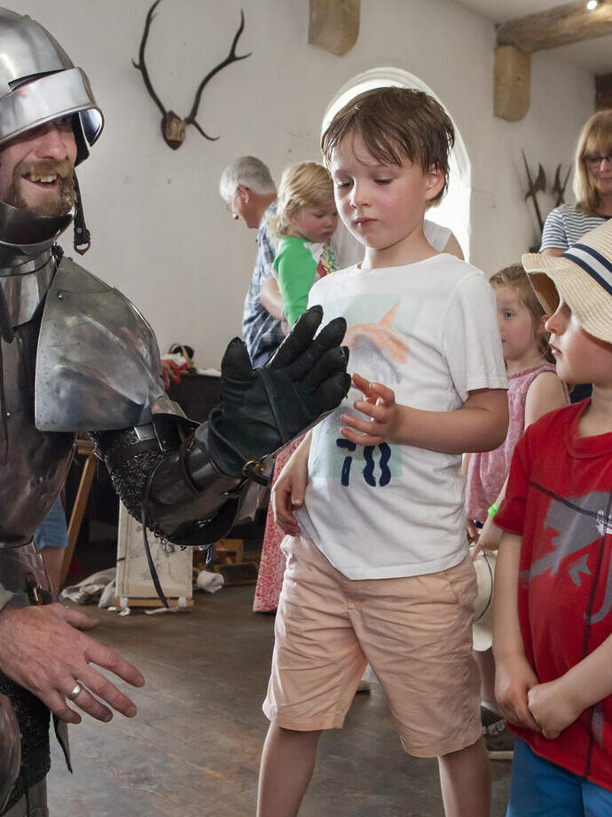 A performer in armor posing with two children at Bolton Castle in Yorkshire