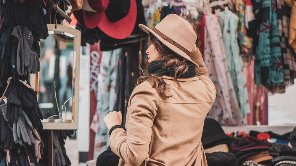 Une femme essayant des chapeaux à un étal du marché de Portobello Road, à Londres