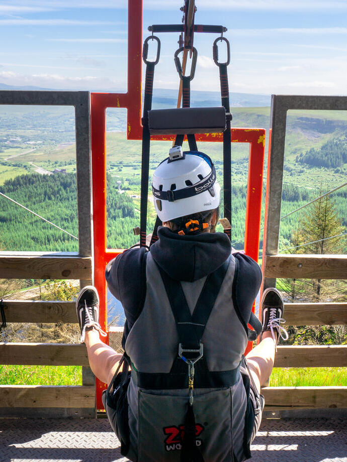 Una persona sta per lanciarsi con una zipline sopra una foresta.