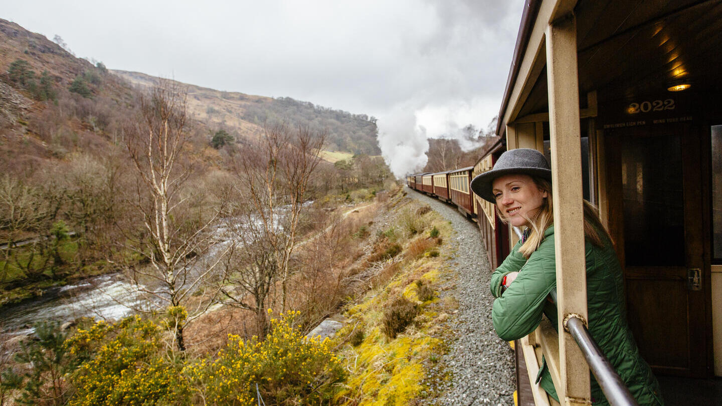 Frau, die sich aus dem Fenster eines Dampfzuges lehnt