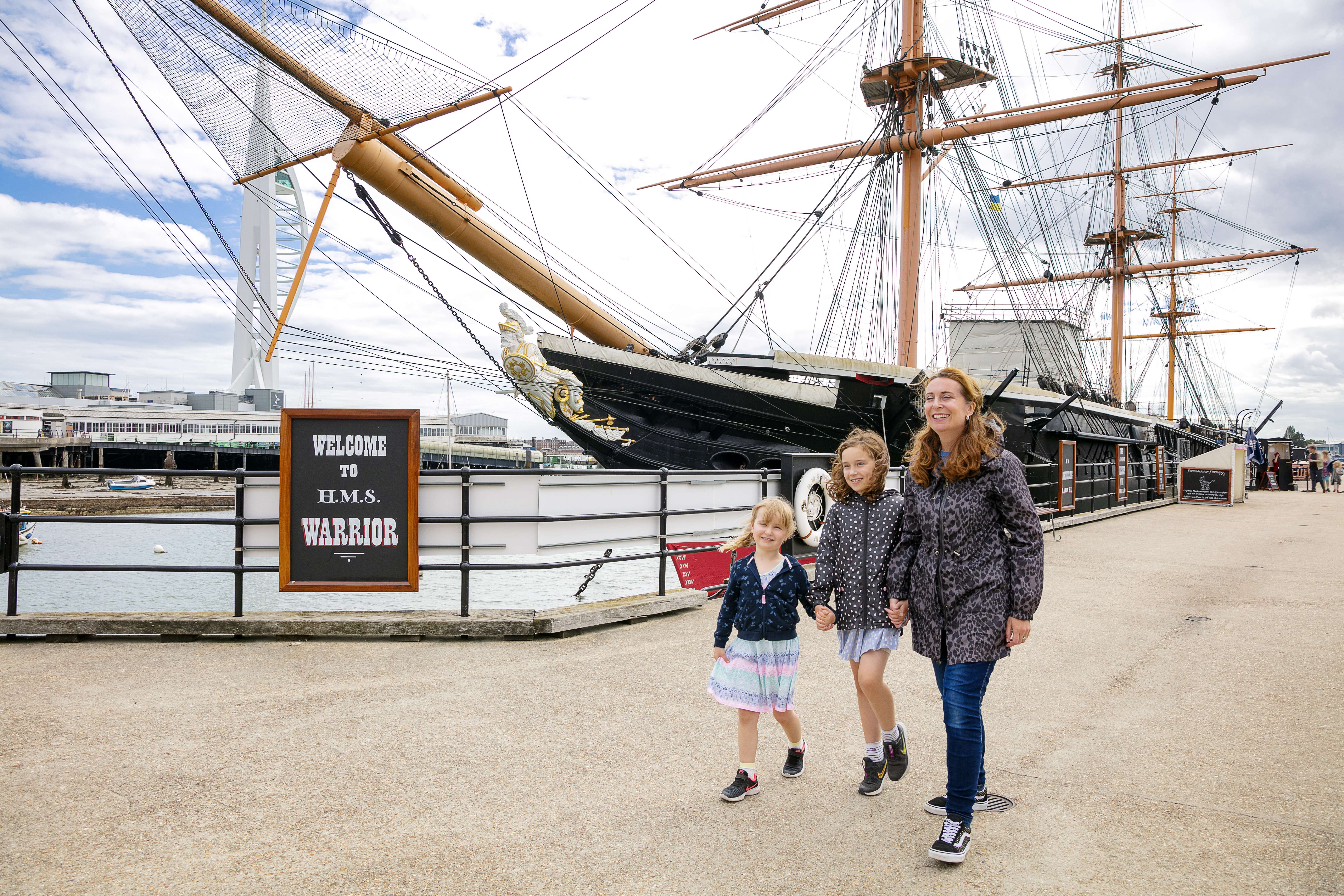 A family walking alongside a ship at a dock