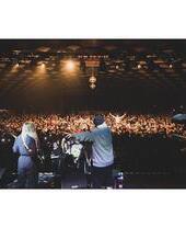 Dos músicos en el escenario mirando a una gran multitud de personas que bailan al ritmo de la música bajo las brillantes luces y las bolas de discoteca en el Barrowland Ballroom de Glasgow