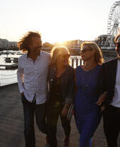 A group of people exploring the harbour of Cardiff at sunset