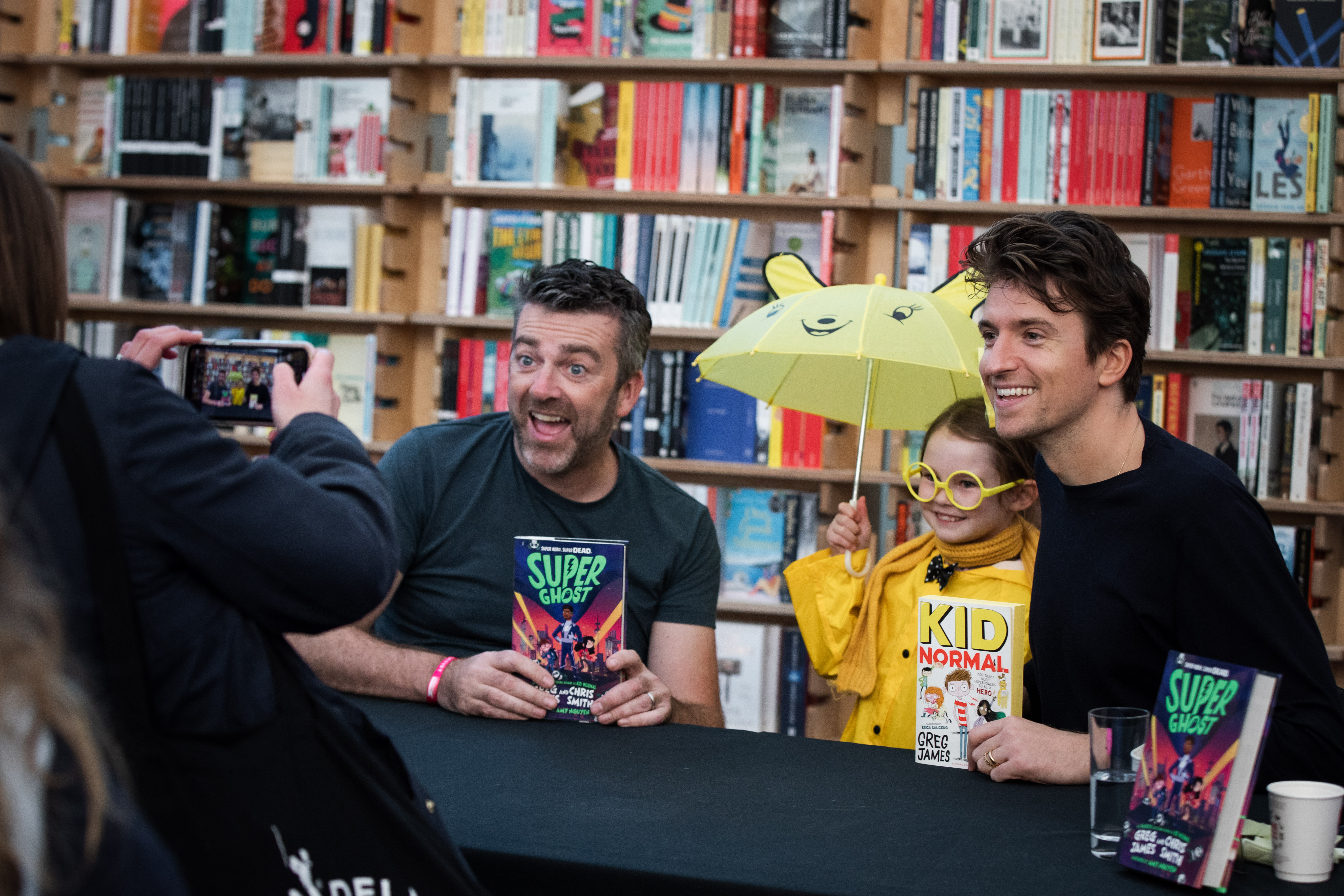 Two men holding books and posing with a child