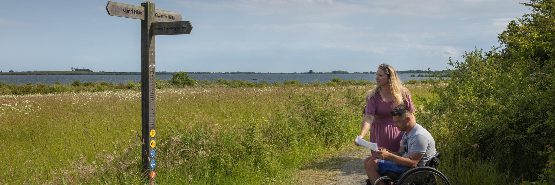 A man who uses a wheelchair and a woman review a map in the countryside