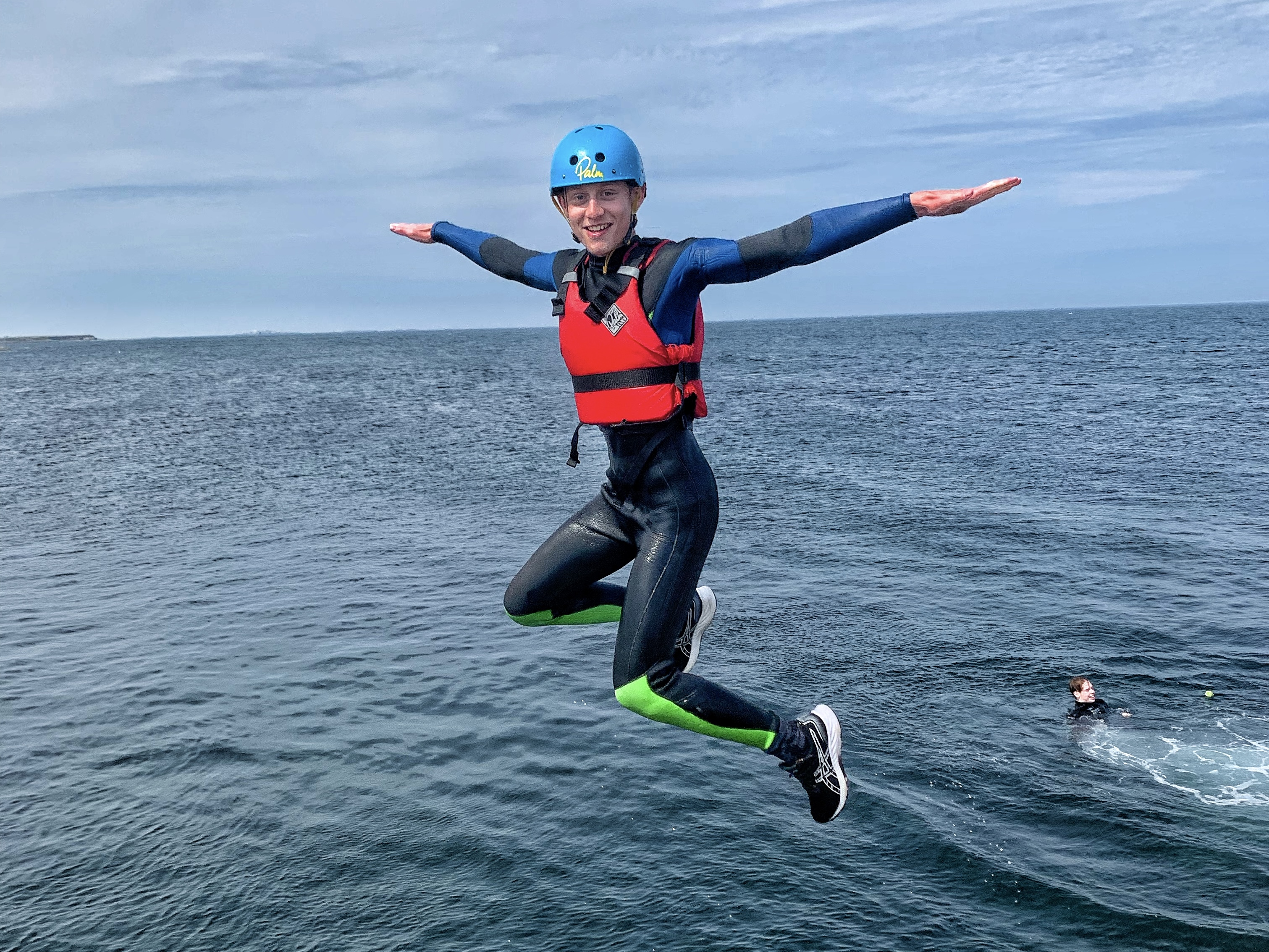 A woman in safety equipment jusmping off a boat into the sea - KA Adventure Sports