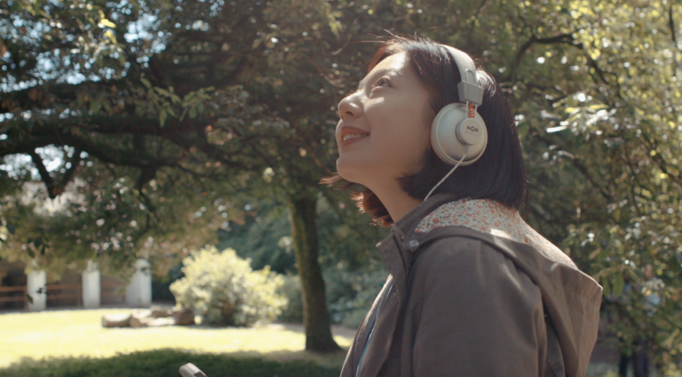 A woman in headphones looking out in a garden at St Fagans National Museum of History, Cardiff