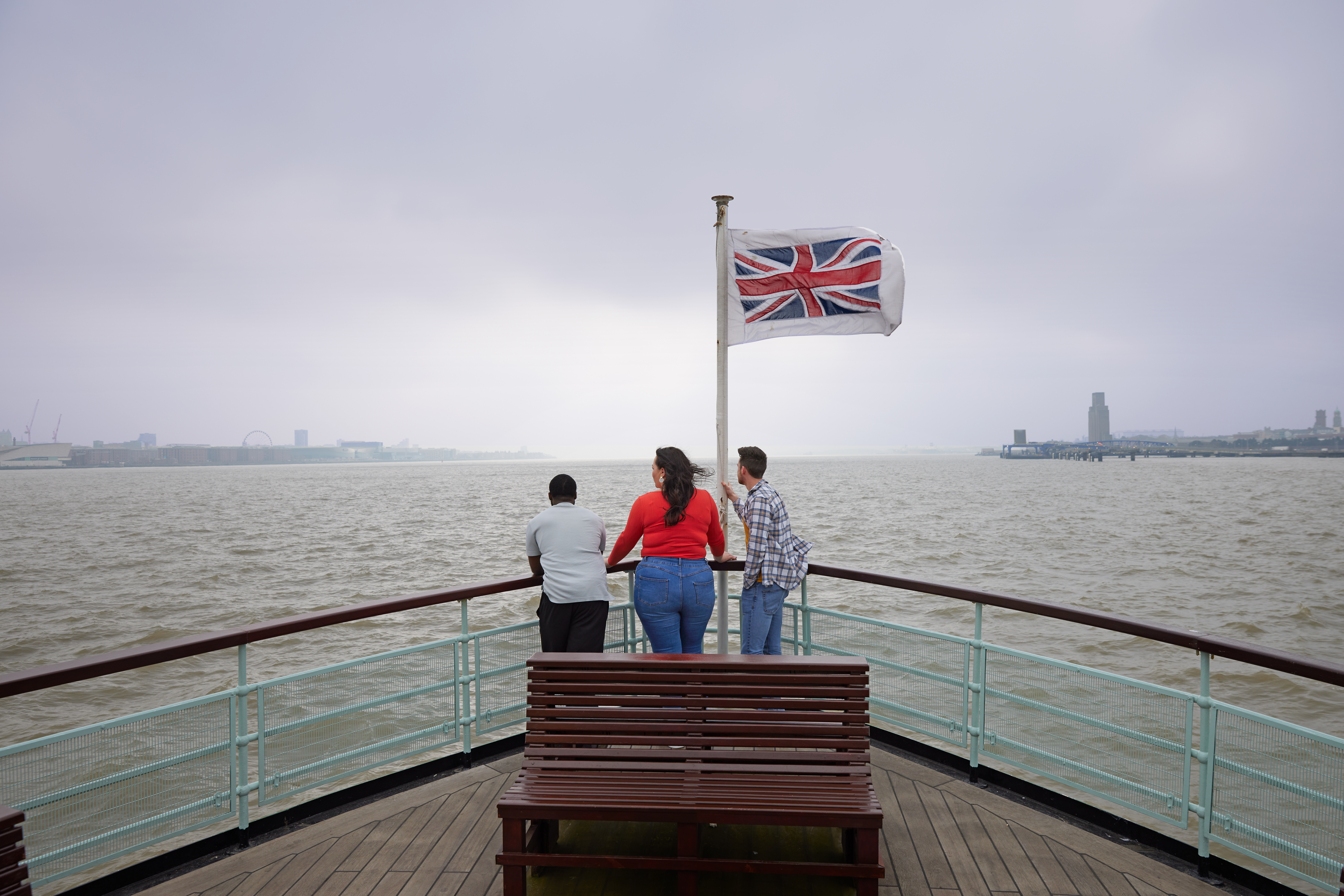 A group of friends, two men and a woman experience ferry ride across a city river.