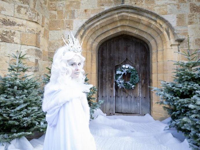 Woman dressed as a white witch outside a castle