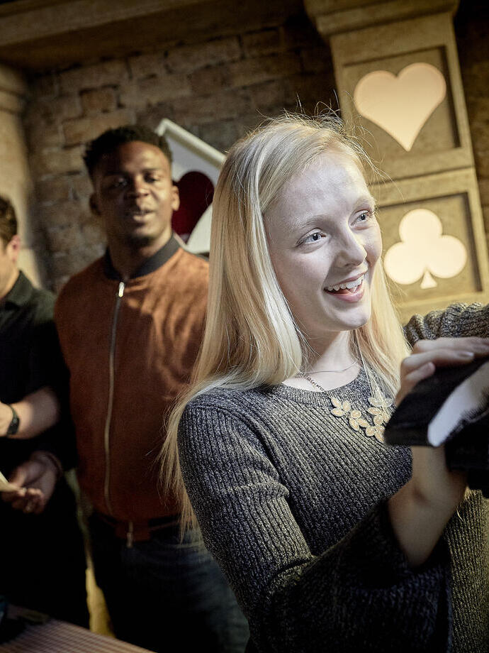 A woman touching an exhibit with two men in the background at Escape Hunt