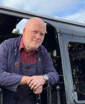 Train driver sticking his head out of a train at Ecclesbourne Valley Railway
