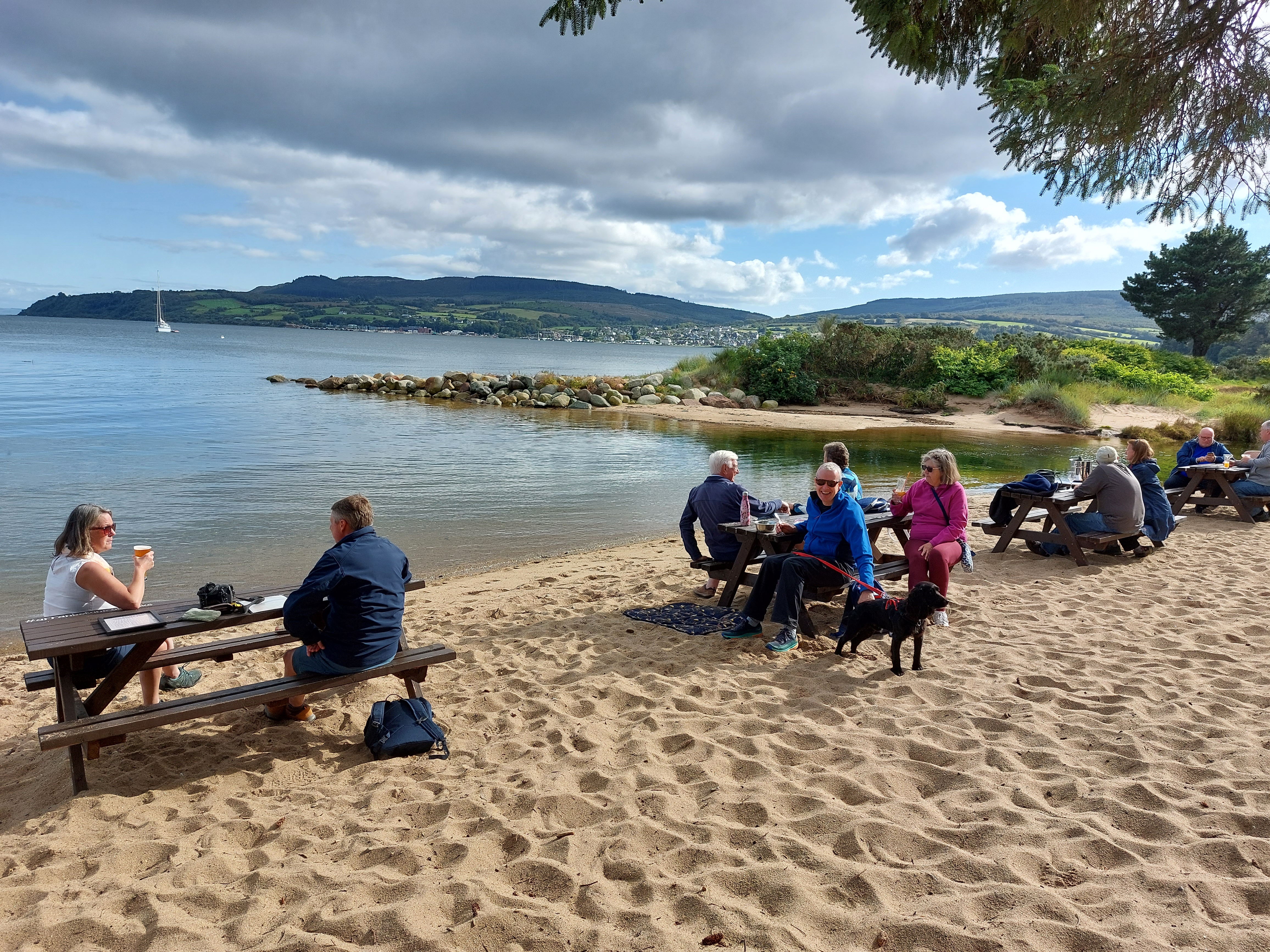 People eating at tables on a beach on the Isle of Arran