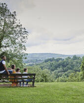Family sit on a bench in park during summer