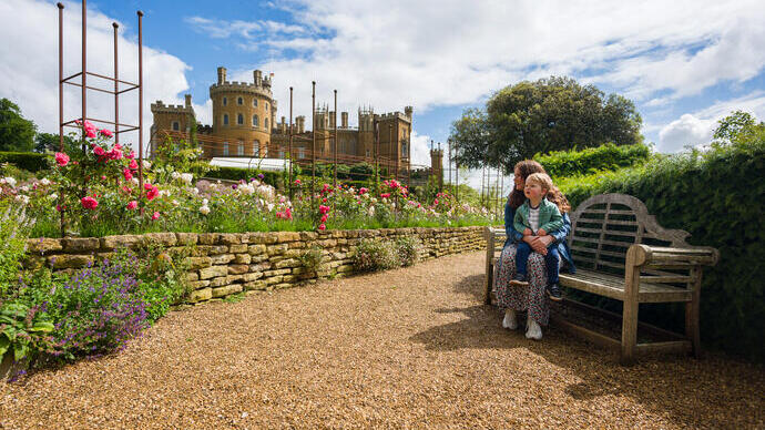 A woman sits on a bench with her child on her lap in front of a castle