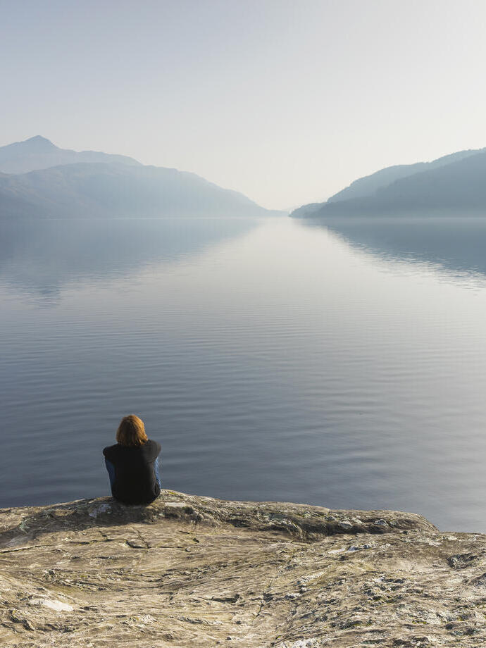 A woman sitting and looking out across Loch Lomond