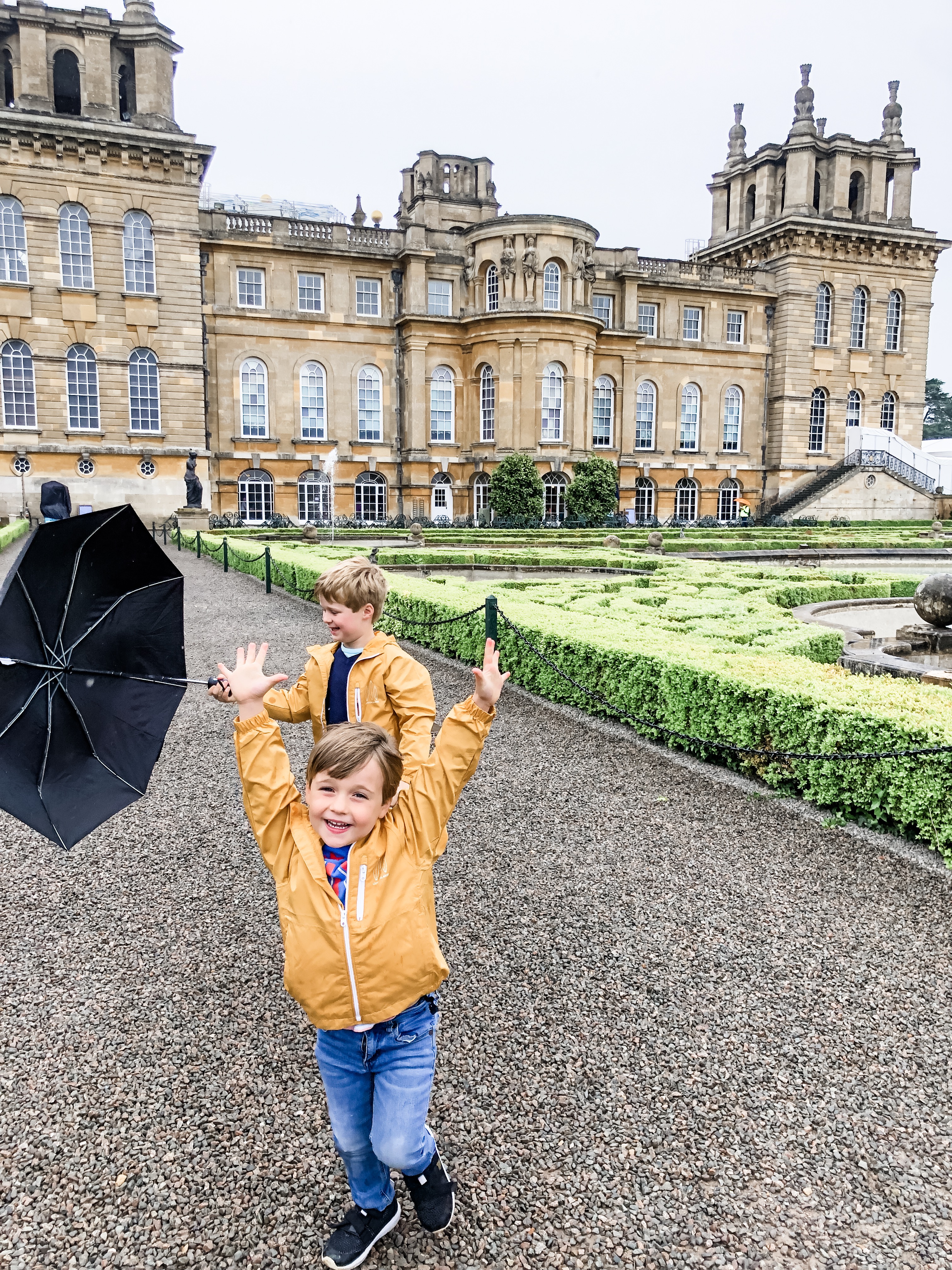 Two children playing in the grounds of a large palace.