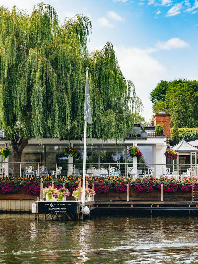 The outdoor decking and seating area of a restaurant terrace overlooking a river.
