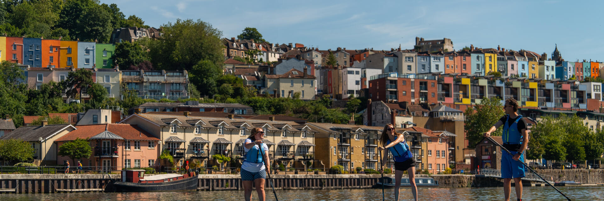 Persone che fanno paddleboarding sul fiume con la città di Bristol sullo sfondo