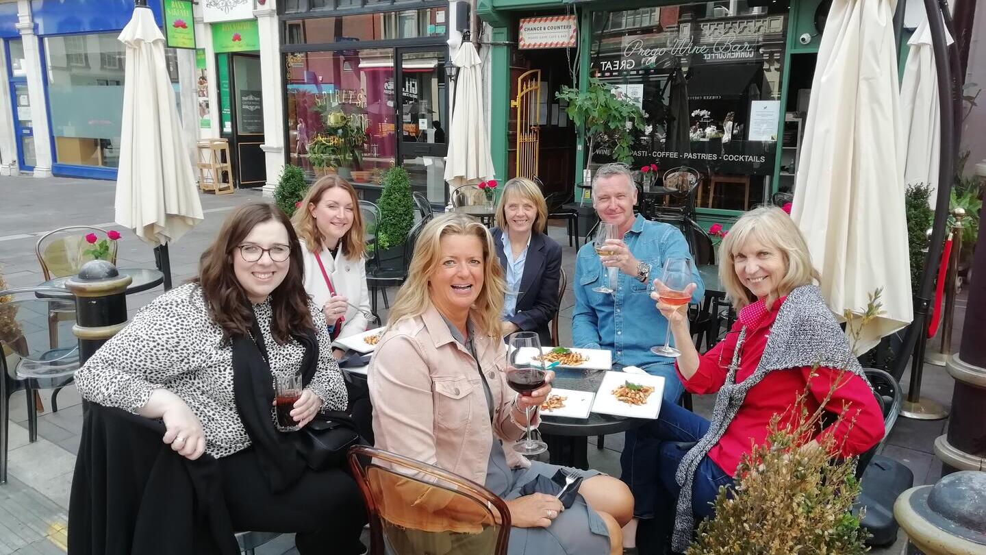 A group of people eating and drinking at an outside table at Cosmo, Cardiff