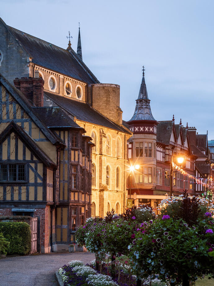 Strada storica ornata di fiori e edifici antichi alla sera.