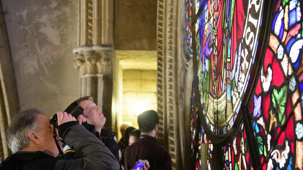 A tour group on a tour of Lincoln Cathedral, looking at a stained glass window