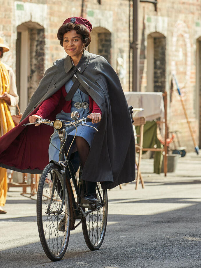 Woman dressed up in 1950's nurse costume riding a bike