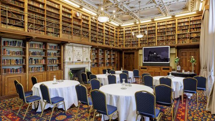 A meeting room laid out with four circular tables & chairs inside a university