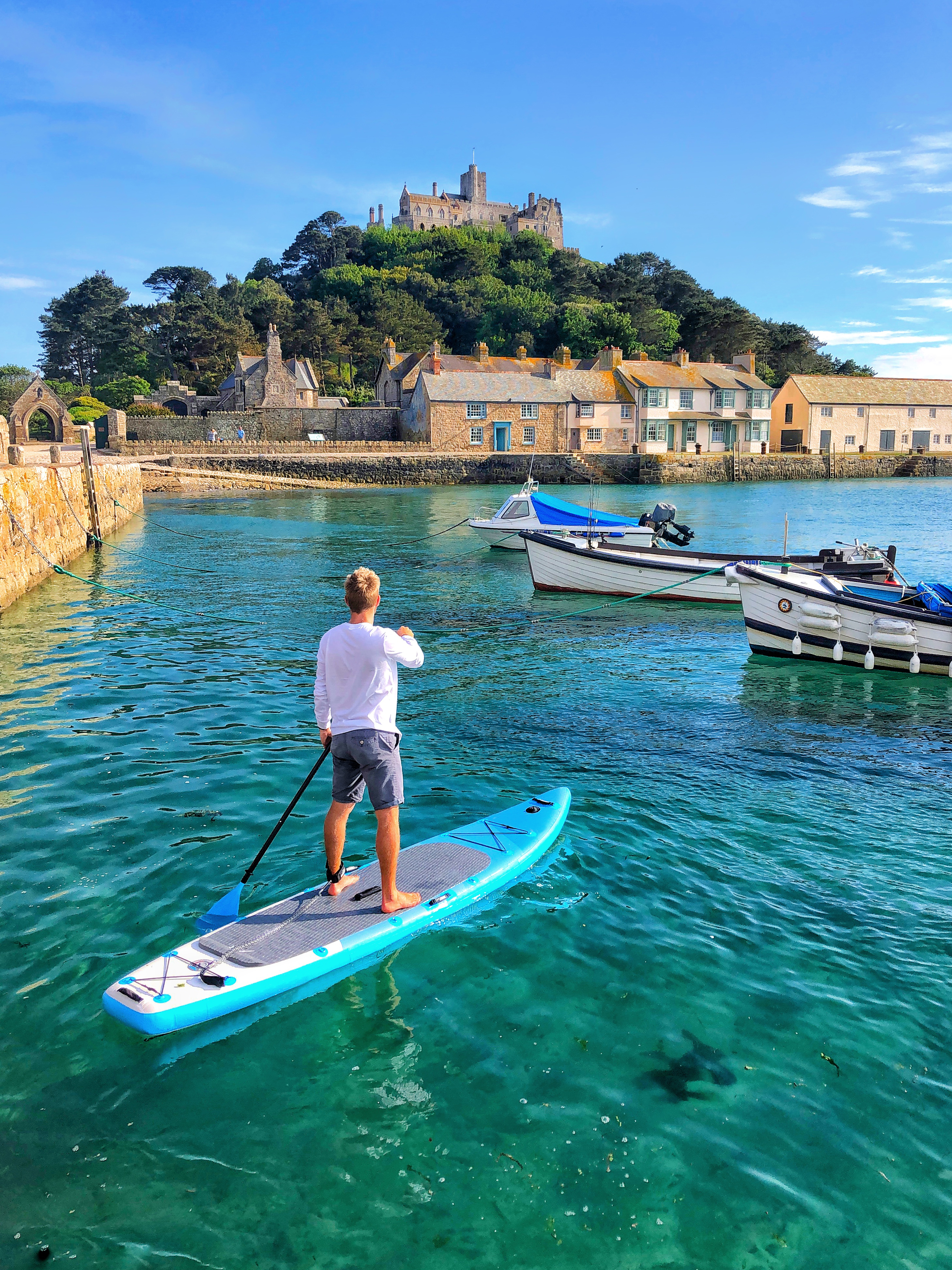 Mann beim Paddeln in einem Hafen in Richtung einer Kirche auf einem Hügel