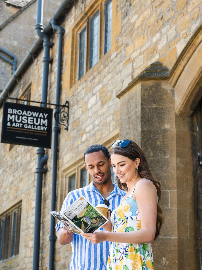 A man and a woman reading a Worcestershire tourism guide outside of a Museum