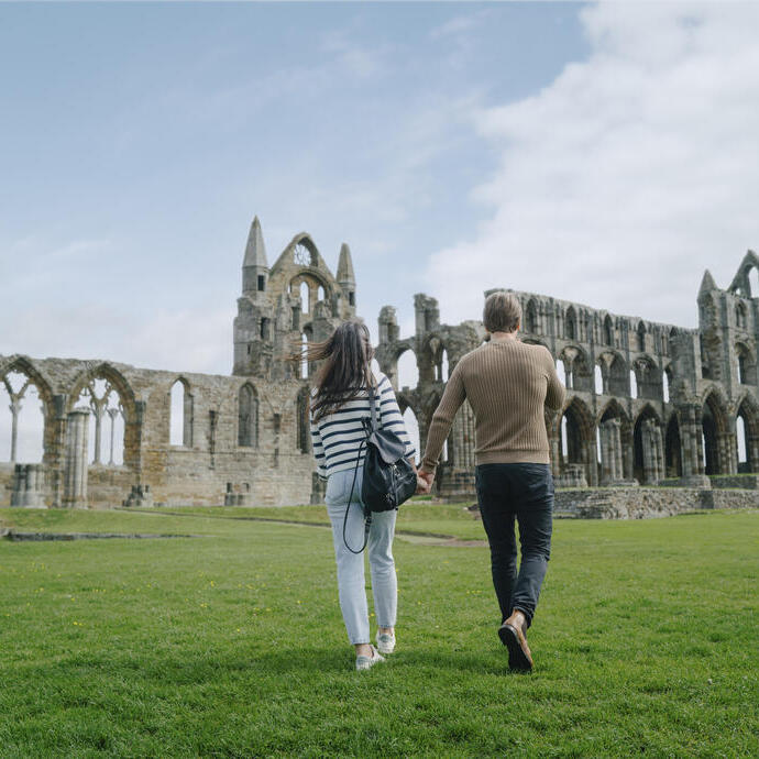 Ein Mann und eine Frau gehen auf ein historisches Abteigebäude zu