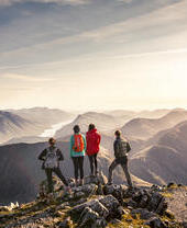 A group of people standing on high point looking at the mountain view below