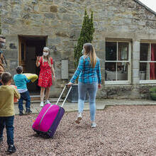 Family arriving at a Bed and Breakfast home, met by the owner