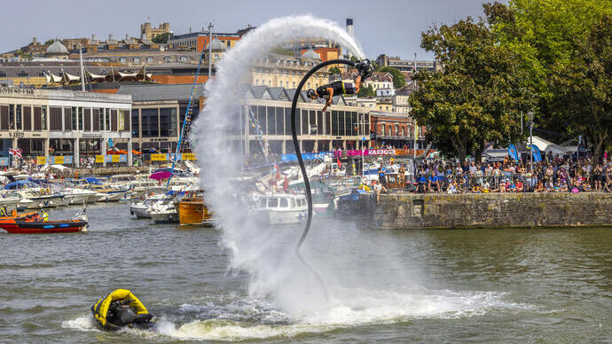 Ein Mann, der im Rahmen des Bristol Harbour Festivals auf einem Wasserstrahl in die Luft springt