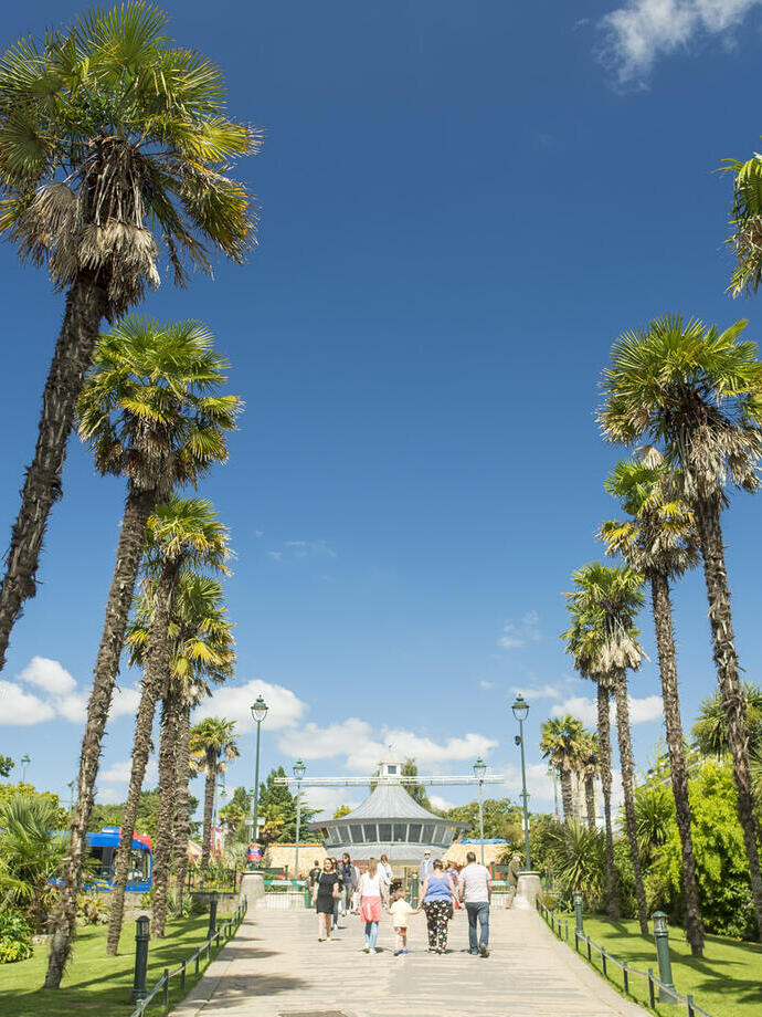People walking through gardens on a sunny day.