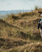 Eine Frau spaziert auf einem Weg im Kenfig National Nature Reserve