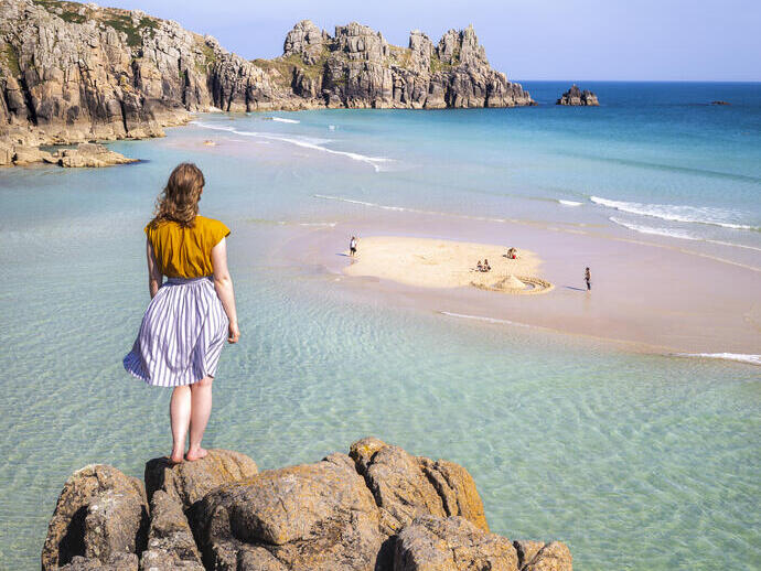 Donna in piedi su una roccia che guarda il mare