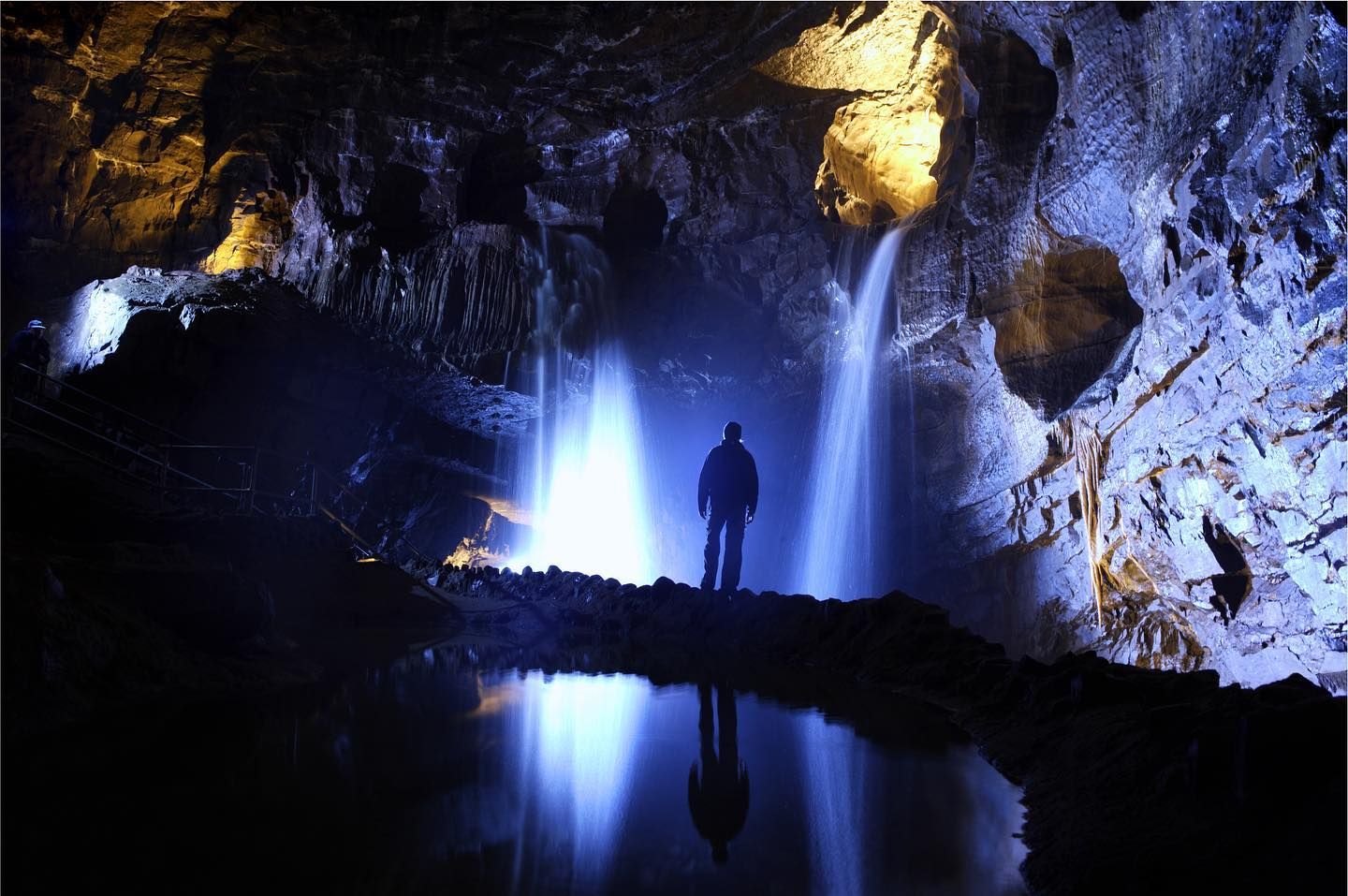 Hombre de pie junto a una cascada en una cueva oscura