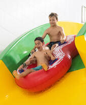 Due bambini che scivolano su un gonfiabile in piscina al The Wave di Coventry