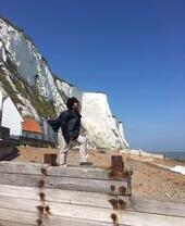 Femme debout sur des épis en bois sur une plage avec des falaises blanches en arrière-plan