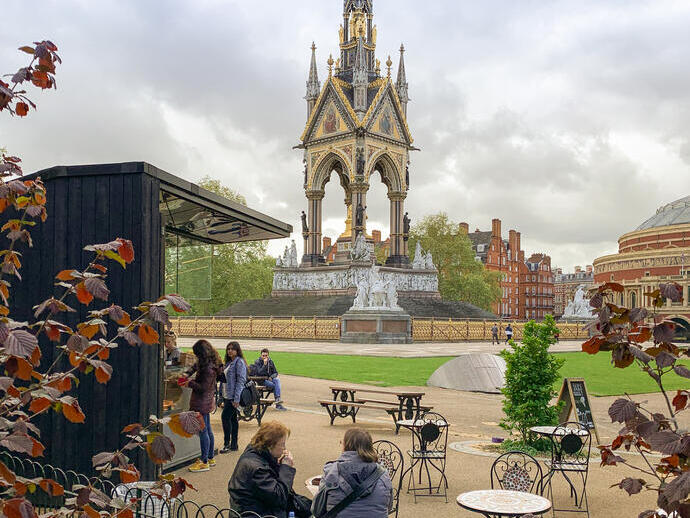 People sitting in an outdoor garden overlooking a large memorial.